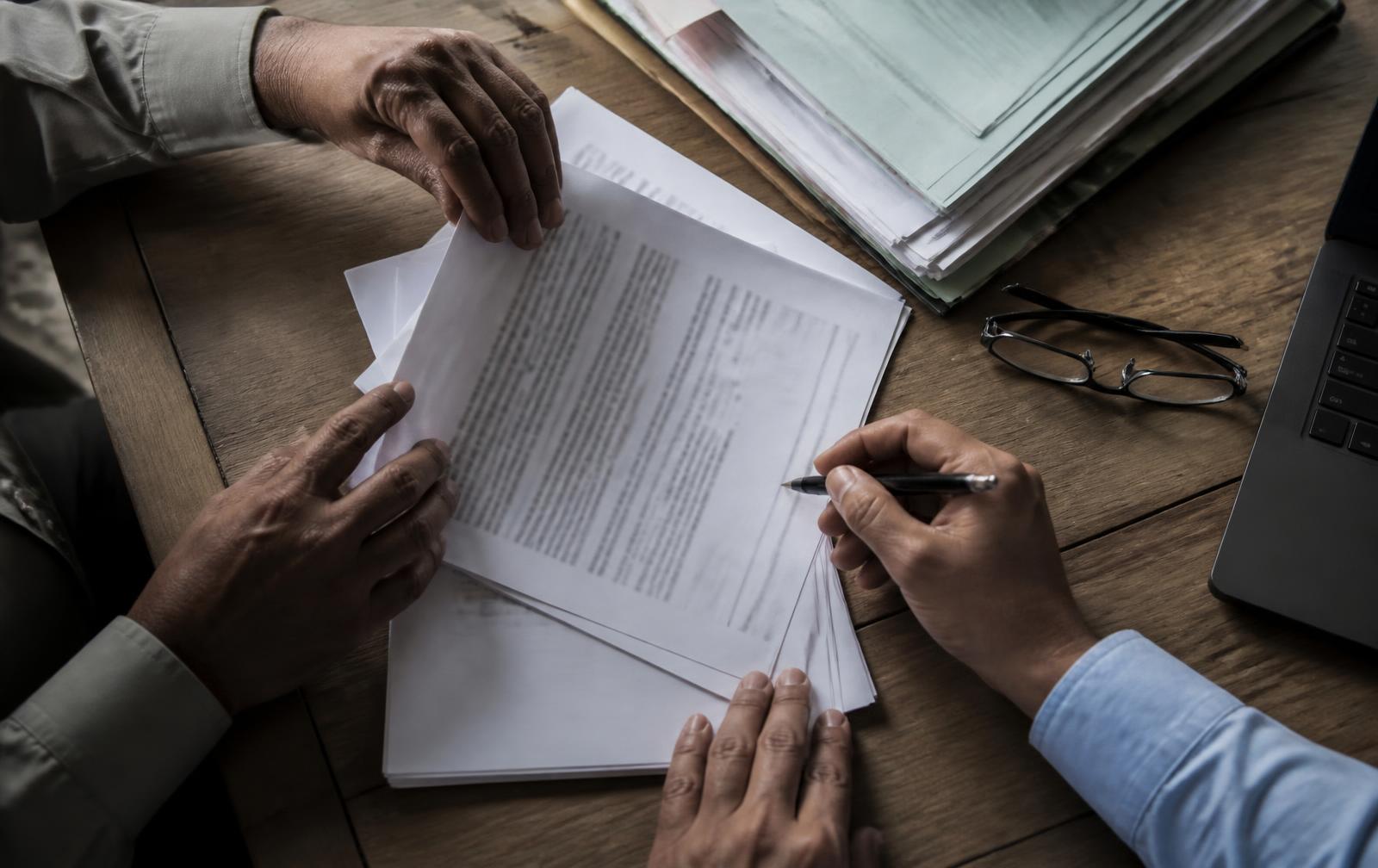 Two people reviewing procurement documents across a desk
